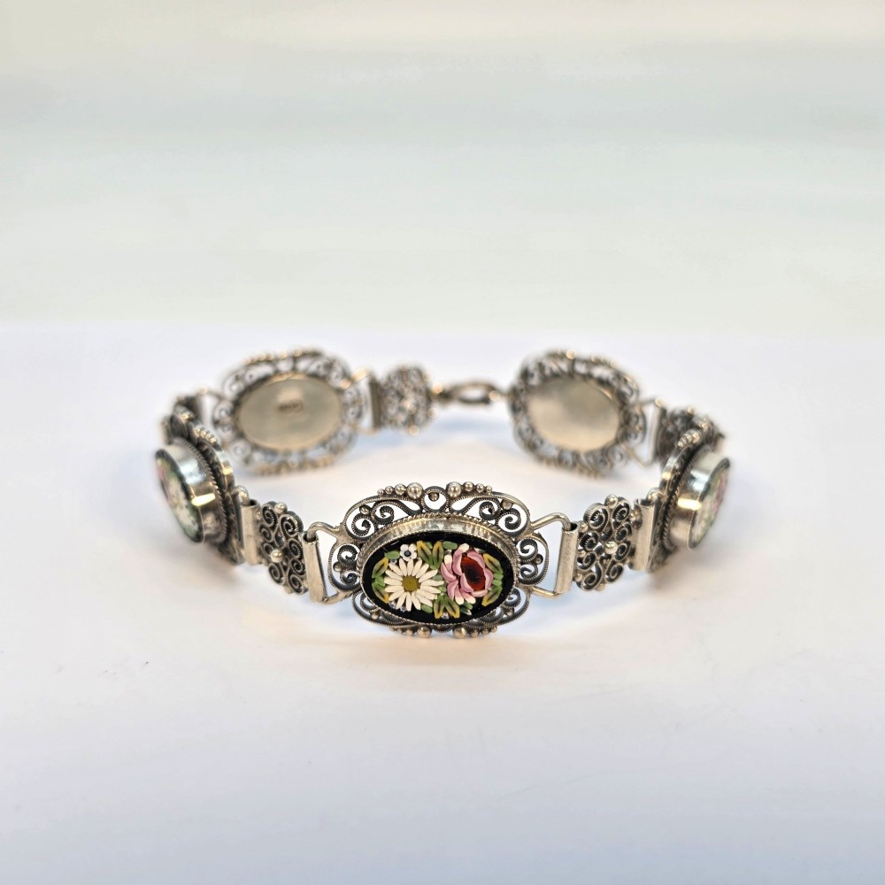 An Italian silver filigree link bracelet featuring oval micro mosaic panels with floral motifs set against a dark background. View IX