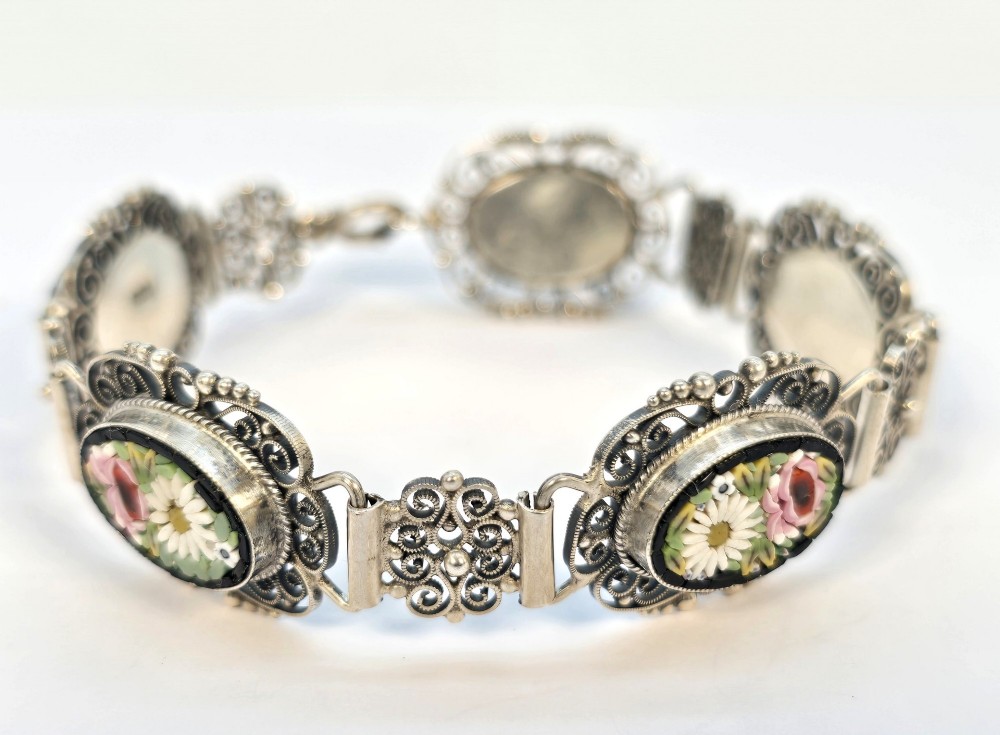 An Italian silver filigree link bracelet featuring oval micro mosaic panels with floral motifs set against a dark background. View X