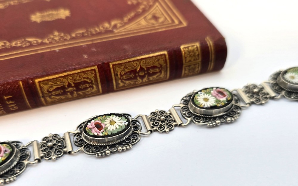 An Italian silver filigree link bracelet featuring oval micro mosaic panels with floral motifs set against a dark background. View XII