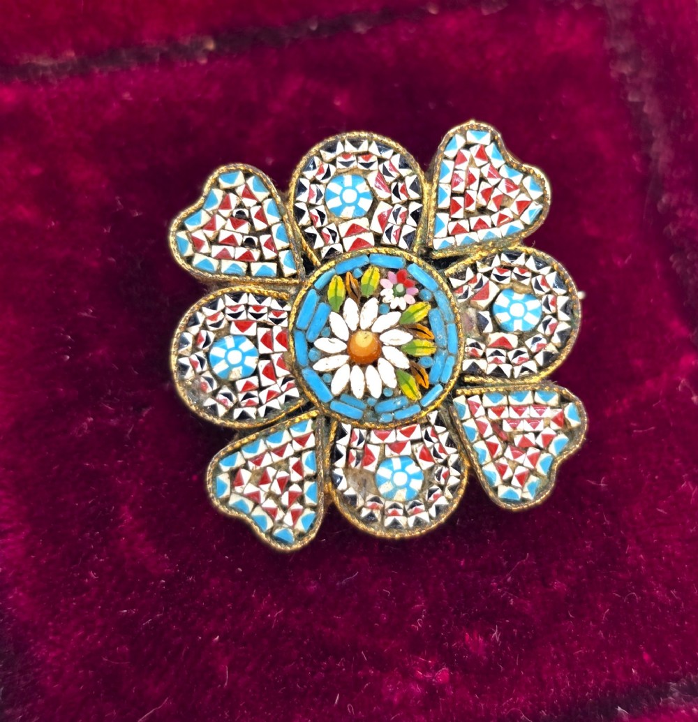 A floral-shaped 19th-century Italian micro mosaic brooch featuring colourful glass tesserae set inside an open velvet-lined tan leather box. View II
