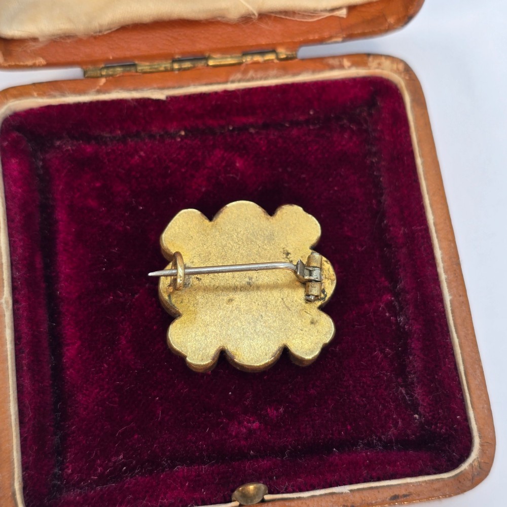 A floral-shaped 19th-century Italian micro mosaic brooch featuring colourful glass tesserae set inside an open velvet-lined tan leather box. View VI