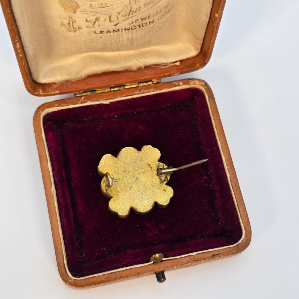 A floral-shaped 19th-century Italian micro mosaic brooch featuring colourful glass tesserae set inside an open velvet-lined tan leather box. View VII