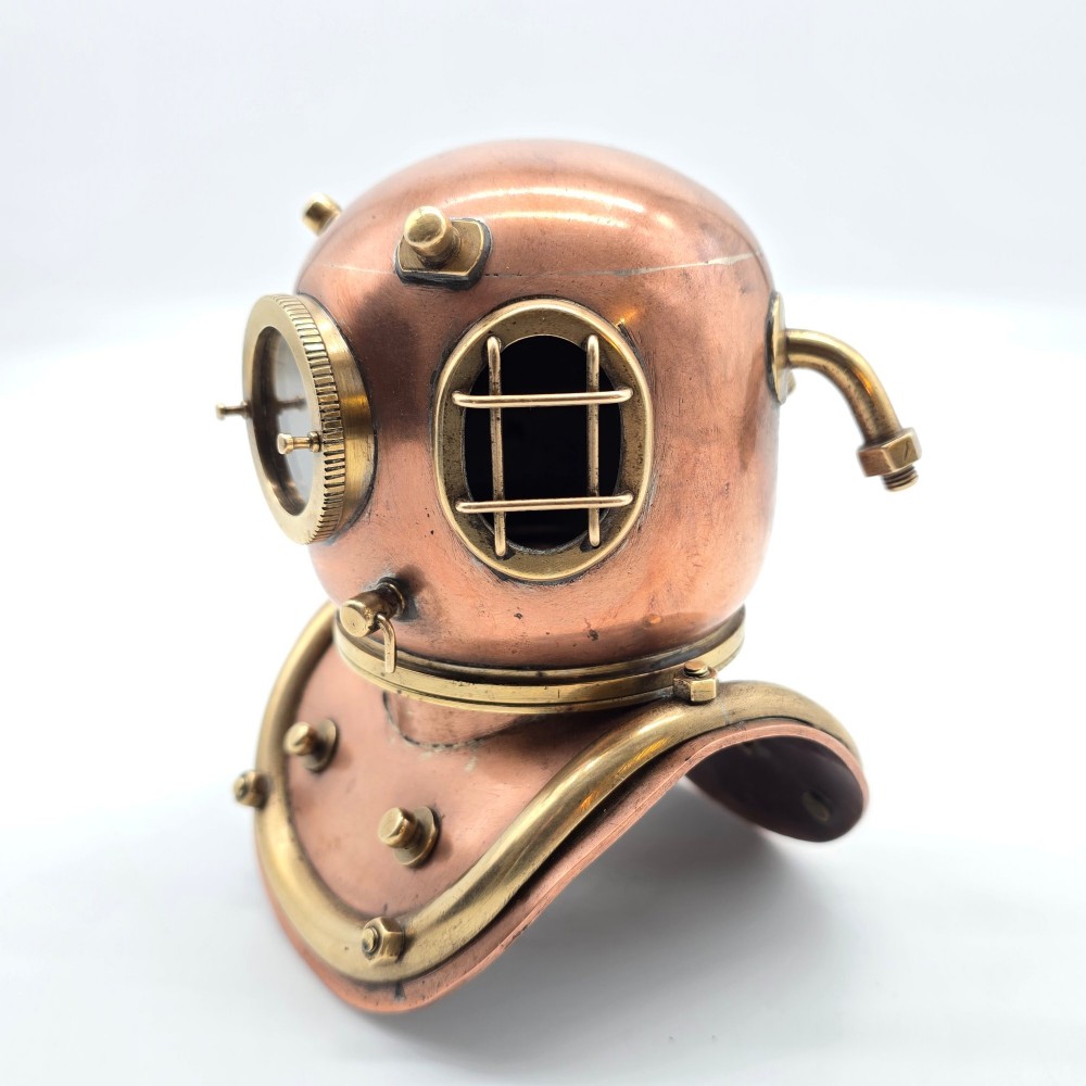 A miniature copper and brass 19th-century style diving helmet with circular glass viewports and a curved corselet base. View XV
