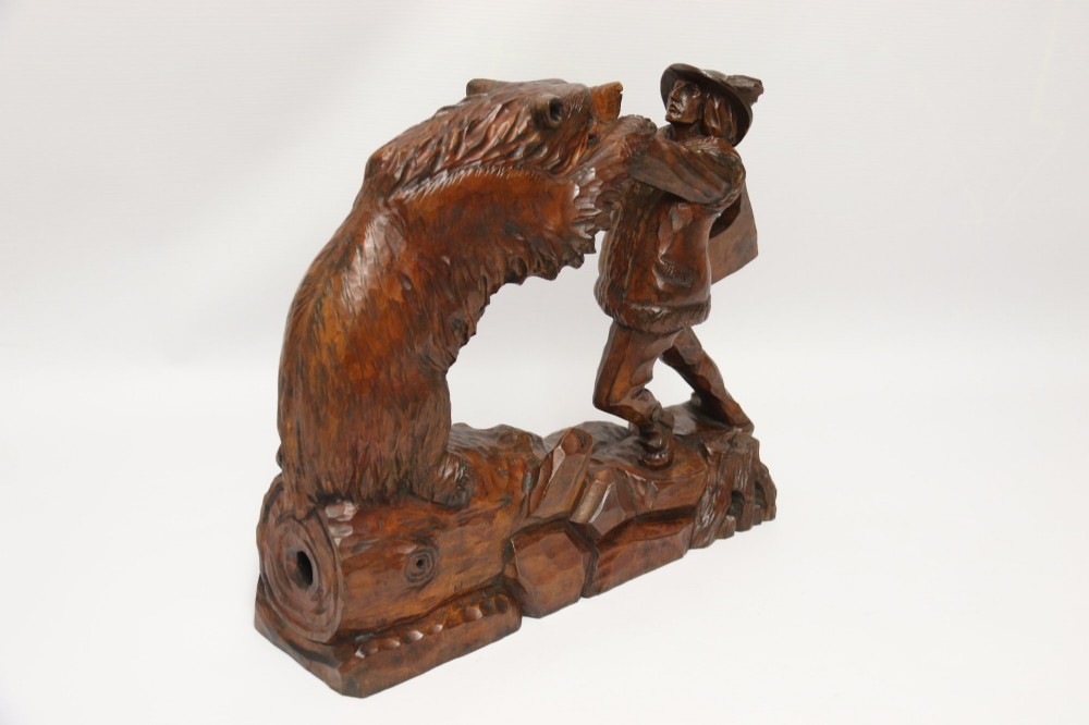 A detailed 19th-century carved walnut sculpture depicting a man in traditional attire struggling with a standing bear upon a carved log base. View V
