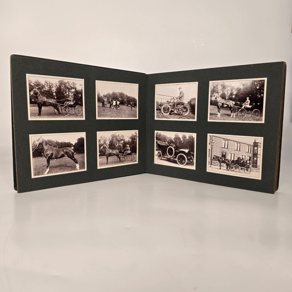 A set of three dark green cloth-bound Edwardian photograph albums stacked diagonally, featuring gold-embossed lettering and a geometric motif. View II