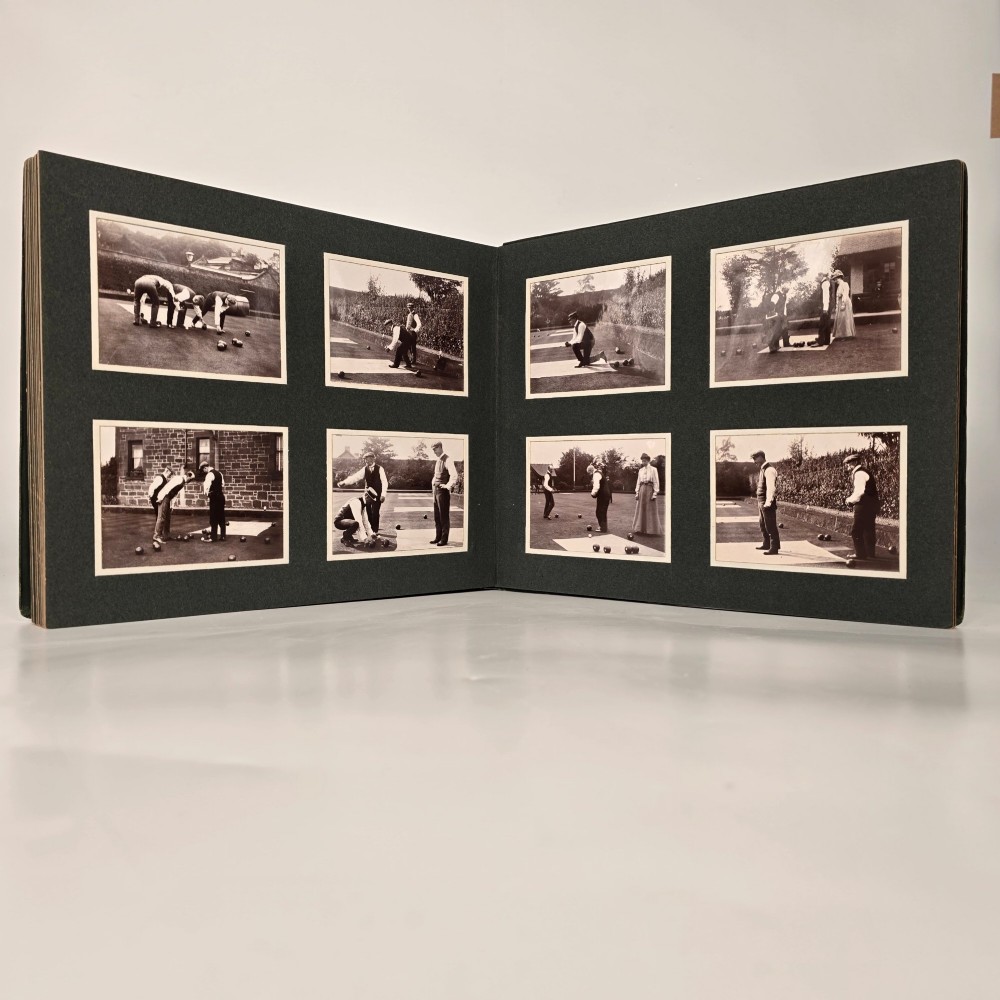 A set of three dark green cloth-bound Edwardian photograph albums stacked diagonally, featuring gold-embossed lettering and a geometric motif. View III
