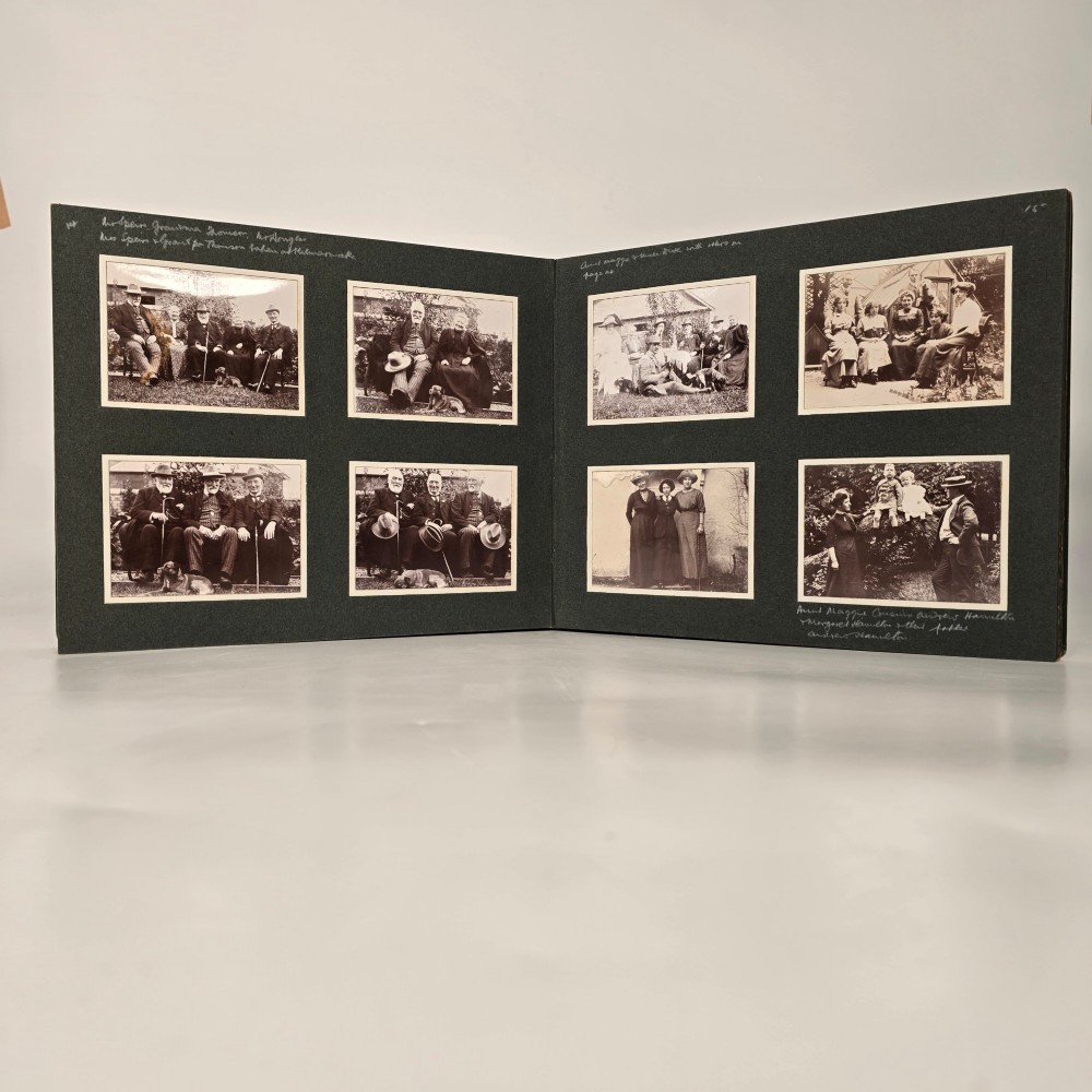 A set of three dark green cloth-bound Edwardian photograph albums stacked diagonally, featuring gold-embossed lettering and a geometric motif. View VI