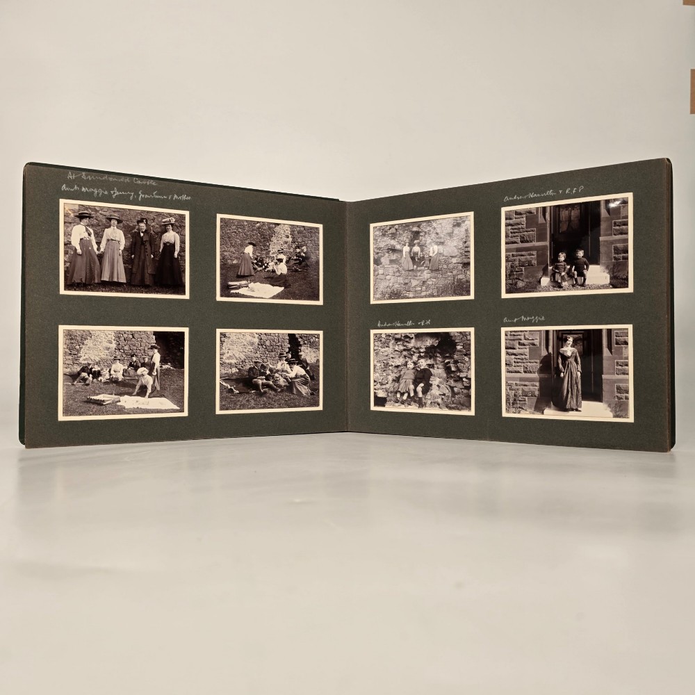 A set of three dark green cloth-bound Edwardian photograph albums stacked diagonally, featuring gold-embossed lettering and a geometric motif. View VIII