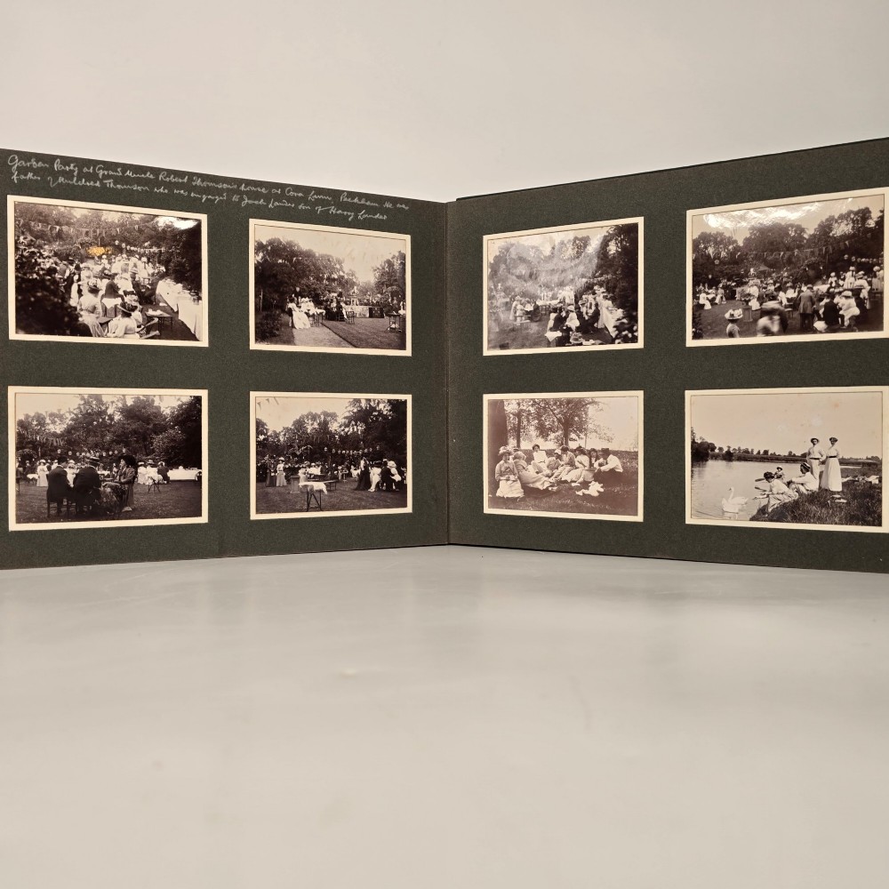 A set of three dark green cloth-bound Edwardian photograph albums stacked diagonally, featuring gold-embossed lettering and a geometric motif. View IX
