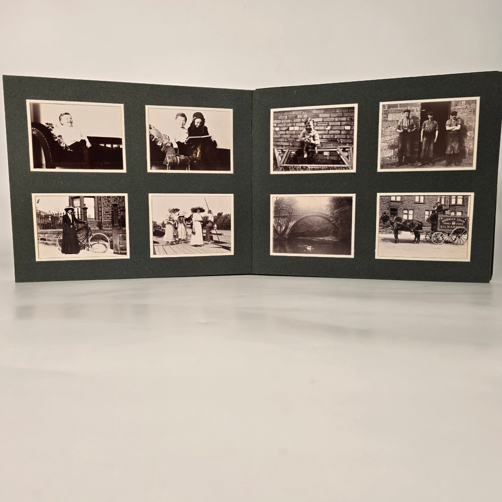 A set of three dark green cloth-bound Edwardian photograph albums stacked diagonally, featuring gold-embossed lettering and a geometric motif. View XV