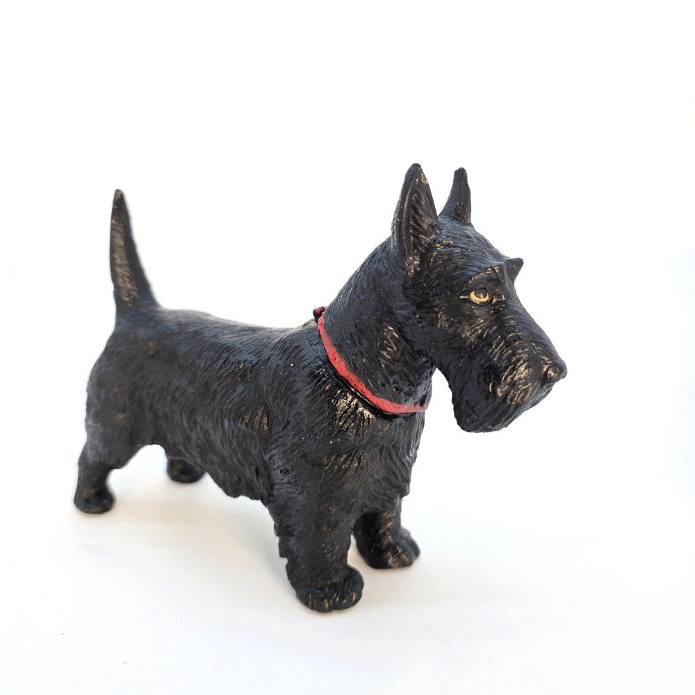 A 1920s black cast metal table lighter crafted in the form of a standing Scottish Terrier with a painted red collar.