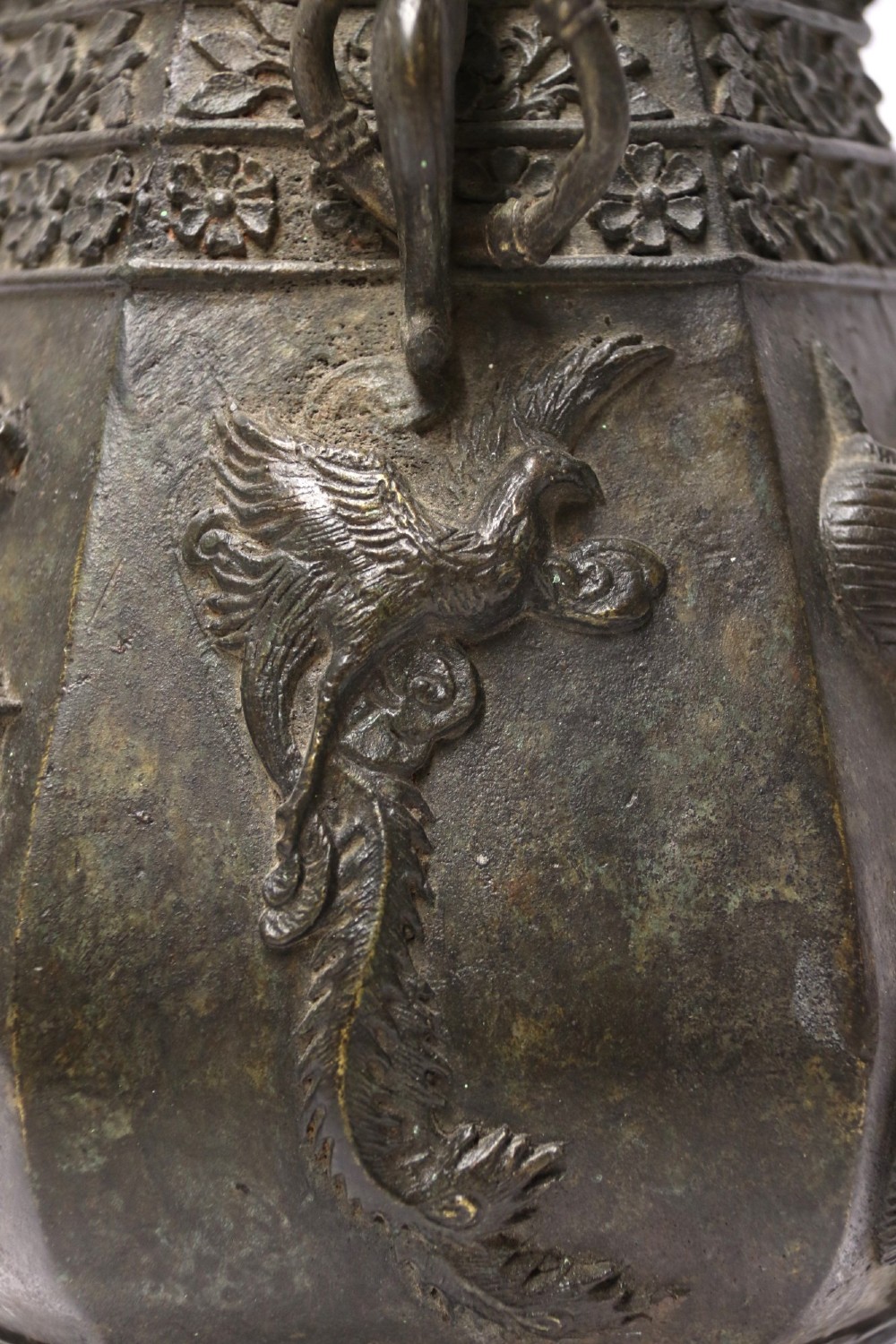 An antique hexagonal solid bronze vessel featuring relief carvings of fish, architectural structures, floral bands, and twin animal-head ring handles. View VI