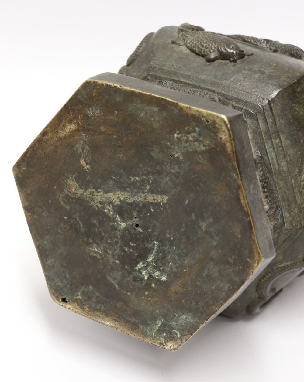 An antique hexagonal solid bronze vessel featuring relief carvings of fish, architectural structures, floral bands, and twin animal-head ring handles. View XIII