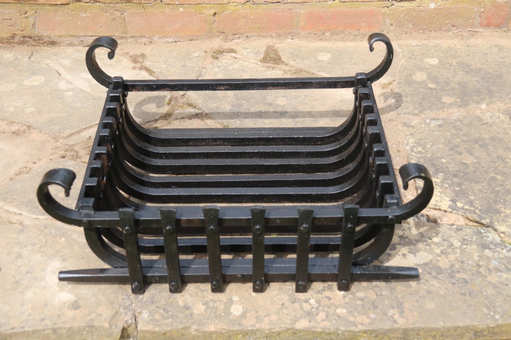 A black wrought iron fire basket featuring vertical slatted bars, hand-riveted joints, and scrolled corner handles. View VI