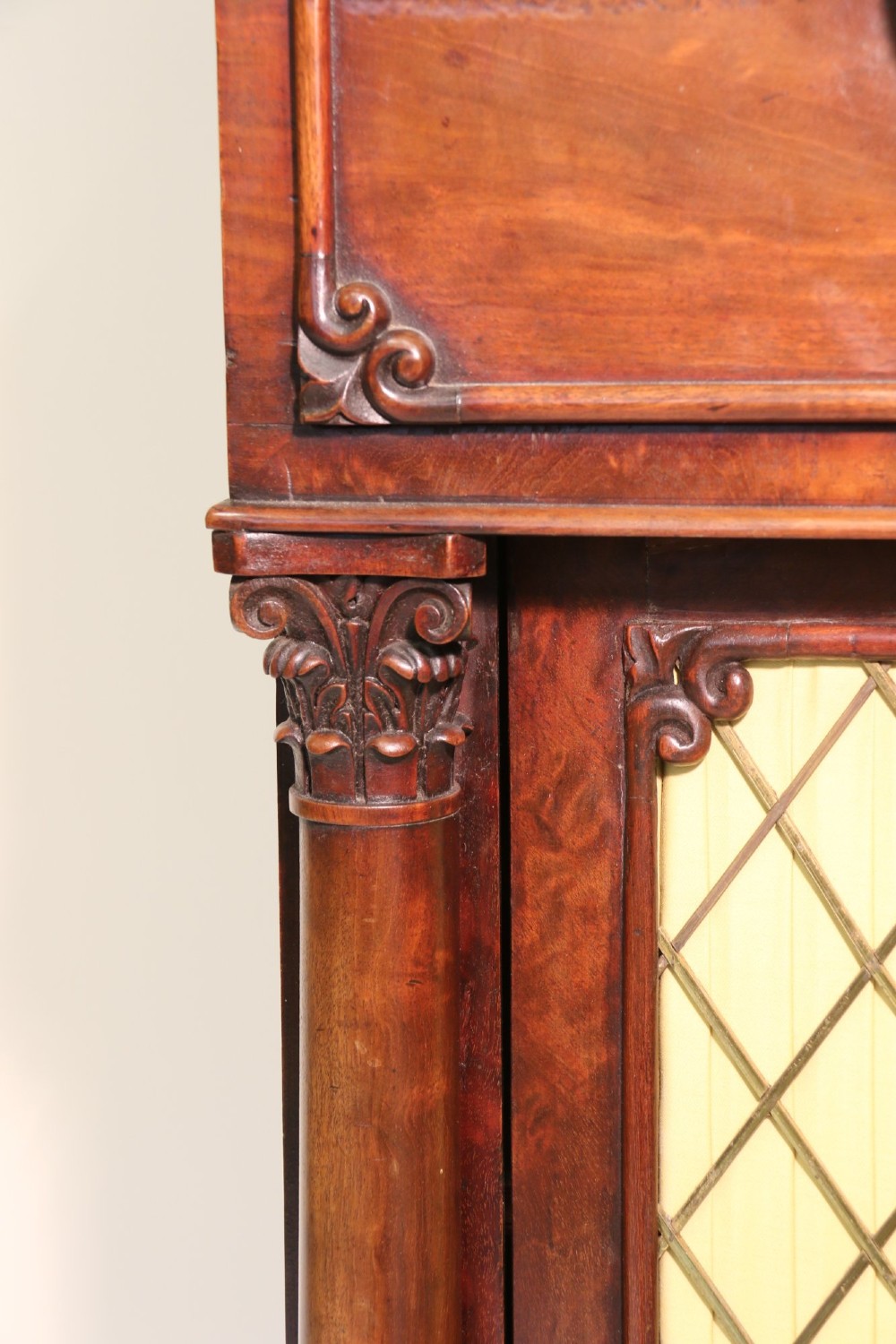A Regency period mahogany secretaire bookcase with a single glazed upper door, a pull-out writing drawer, and a lower door with fabric and brass grille. View IX