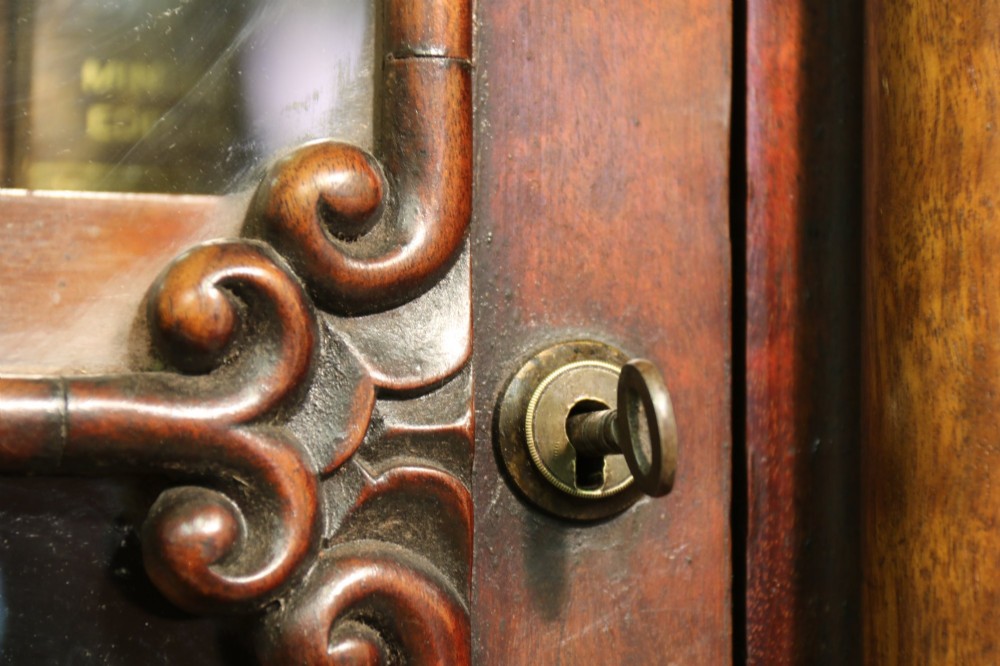 A Regency period mahogany secretaire bookcase with a single glazed upper door, a pull-out writing drawer, and a lower door with fabric and brass grille. View XII