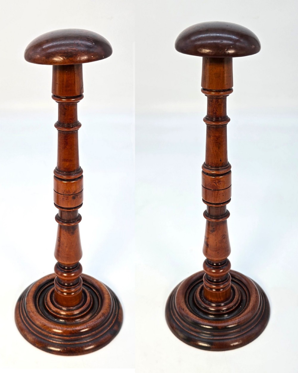 A pair of turned early eighteenth-century yew wood wig stands featuring domed tops, knopped baluster shafts, and turned circular bases.