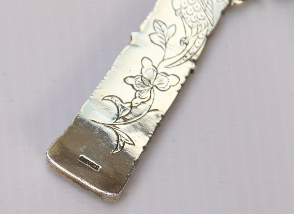 An antique Chinese magnifying glass featuring an ornate repousse silver circular frame decorated with squirrels and grapevines attached to a carved off-white jade handle. View XIII