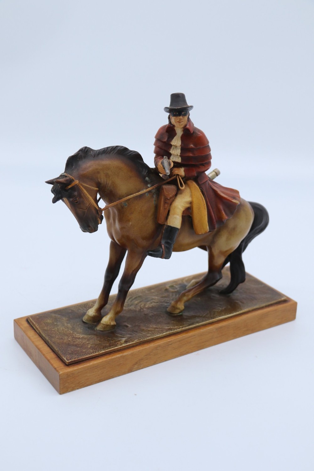 An Art Deco cold-painted metal table lighter depicting a masked figure on horseback mounted on a wooden base. View II