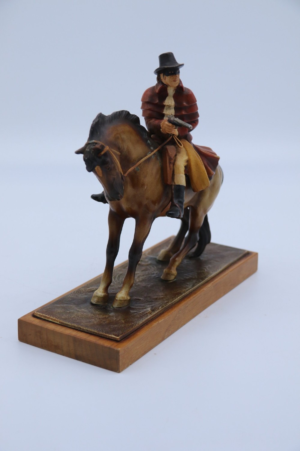 An Art Deco cold-painted metal table lighter depicting a masked figure on horseback mounted on a wooden base. View III