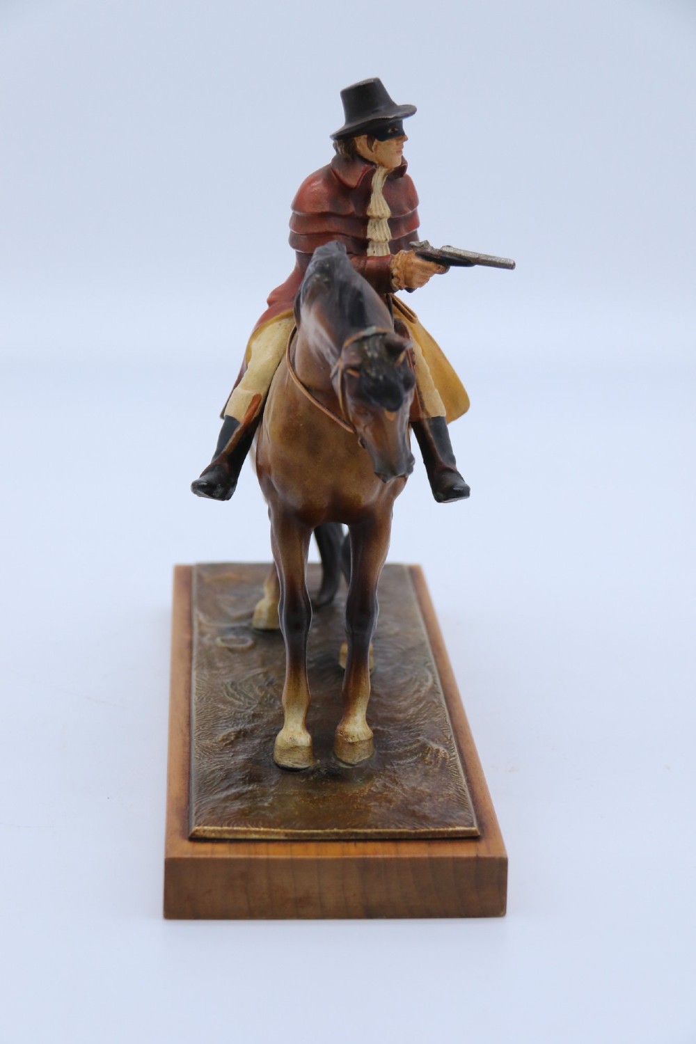 An Art Deco cold-painted metal table lighter depicting a masked figure on horseback mounted on a wooden base. View IV