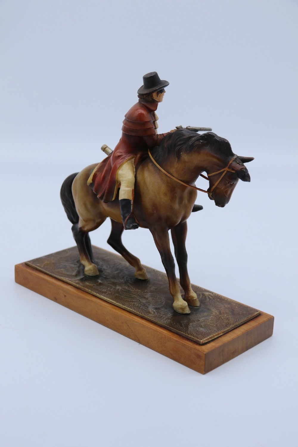 An Art Deco cold-painted metal table lighter depicting a masked figure on horseback mounted on a wooden base. View V