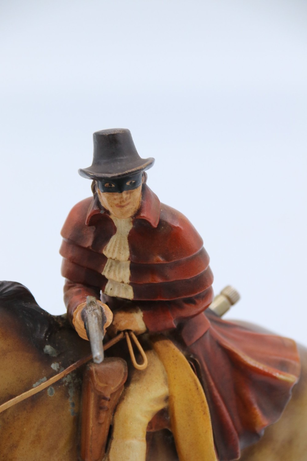 An Art Deco cold-painted metal table lighter depicting a masked figure on horseback mounted on a wooden base. View VI