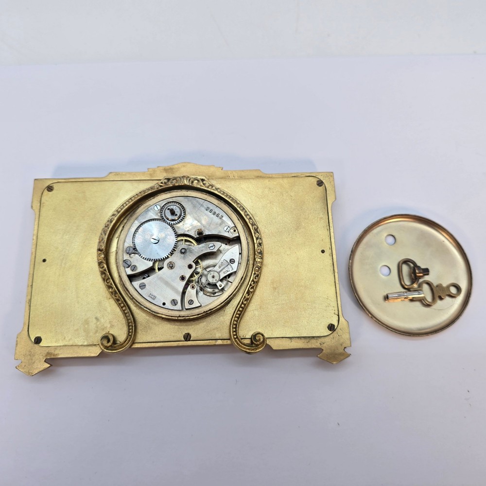 A rectangular gilt brass Art Deco strut clock featuring an illustrated courtly scene on the central dial surrounded by numeric markers. View XI