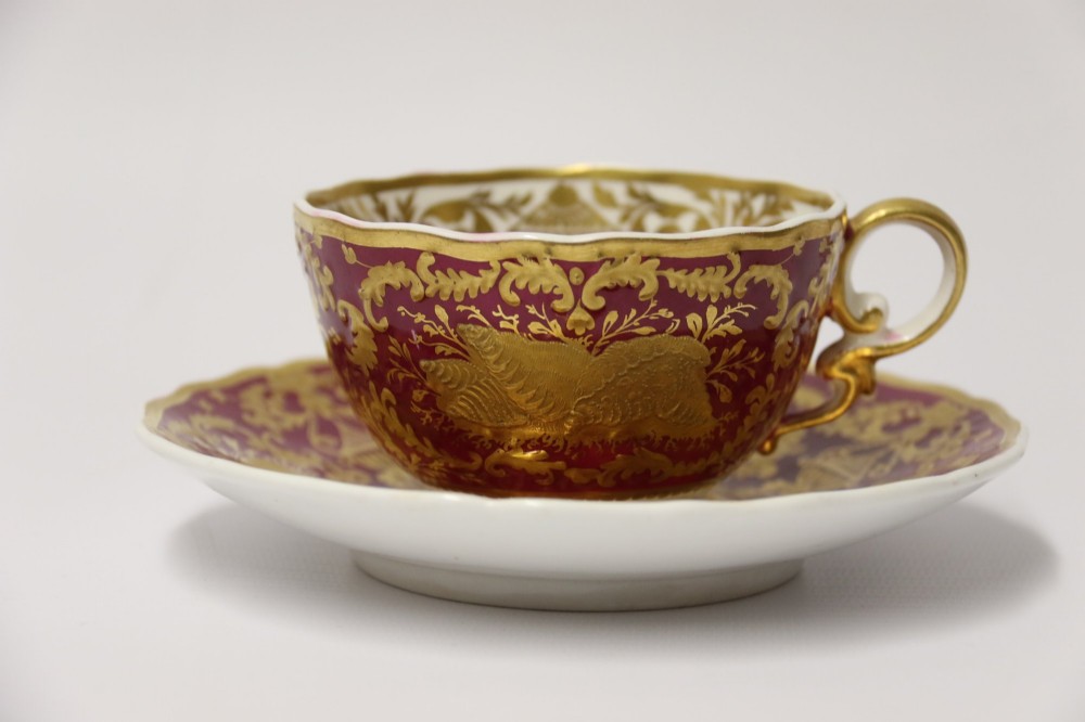 An early nineteenth-century Regency Spode porcelain cabinet cup and saucer featuring deep crimson ground decorated with heavy gilded scrollwork and shell motifs. View III