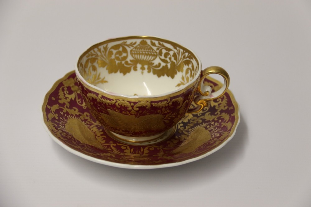 An early nineteenth-century Regency Spode porcelain cabinet cup and saucer featuring deep crimson ground decorated with heavy gilded scrollwork and shell motifs. View X