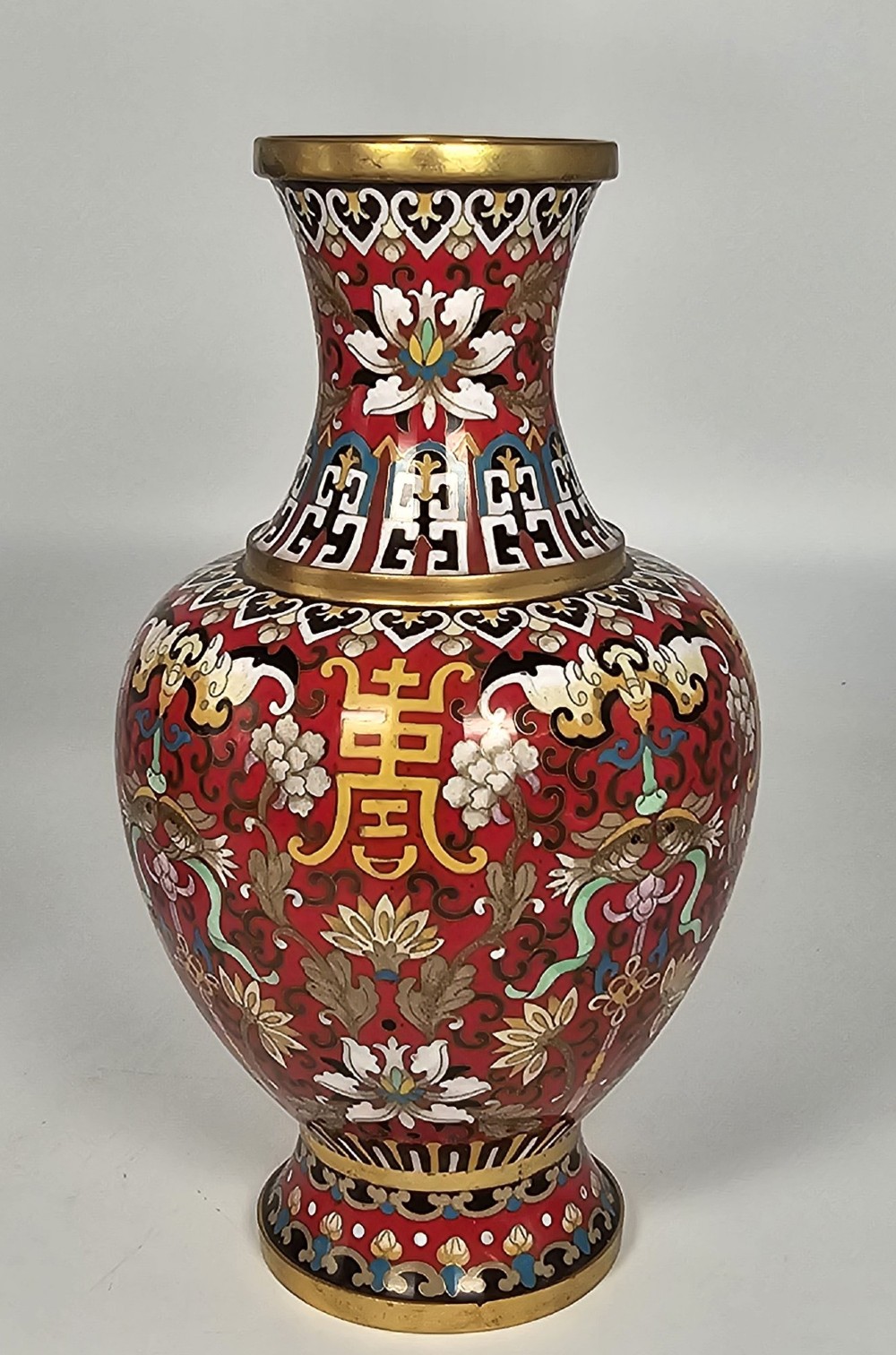 A matching pair of baluster-form Chinese cloisonne enamel vases with red backgrounds, lotus motifs, auspicious symbols, and gilt rims. View V