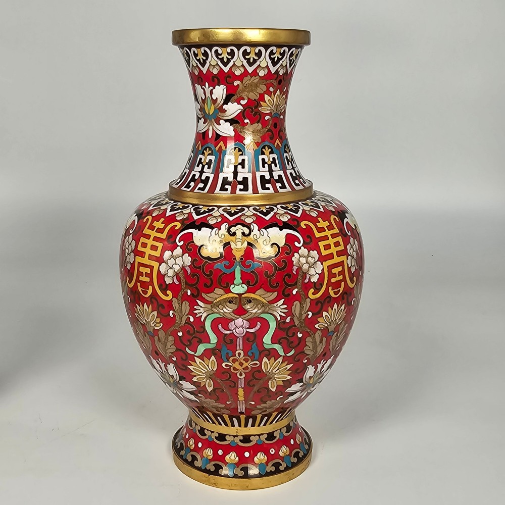 A matching pair of baluster-form Chinese cloisonne enamel vases with red backgrounds, lotus motifs, auspicious symbols, and gilt rims. View VI