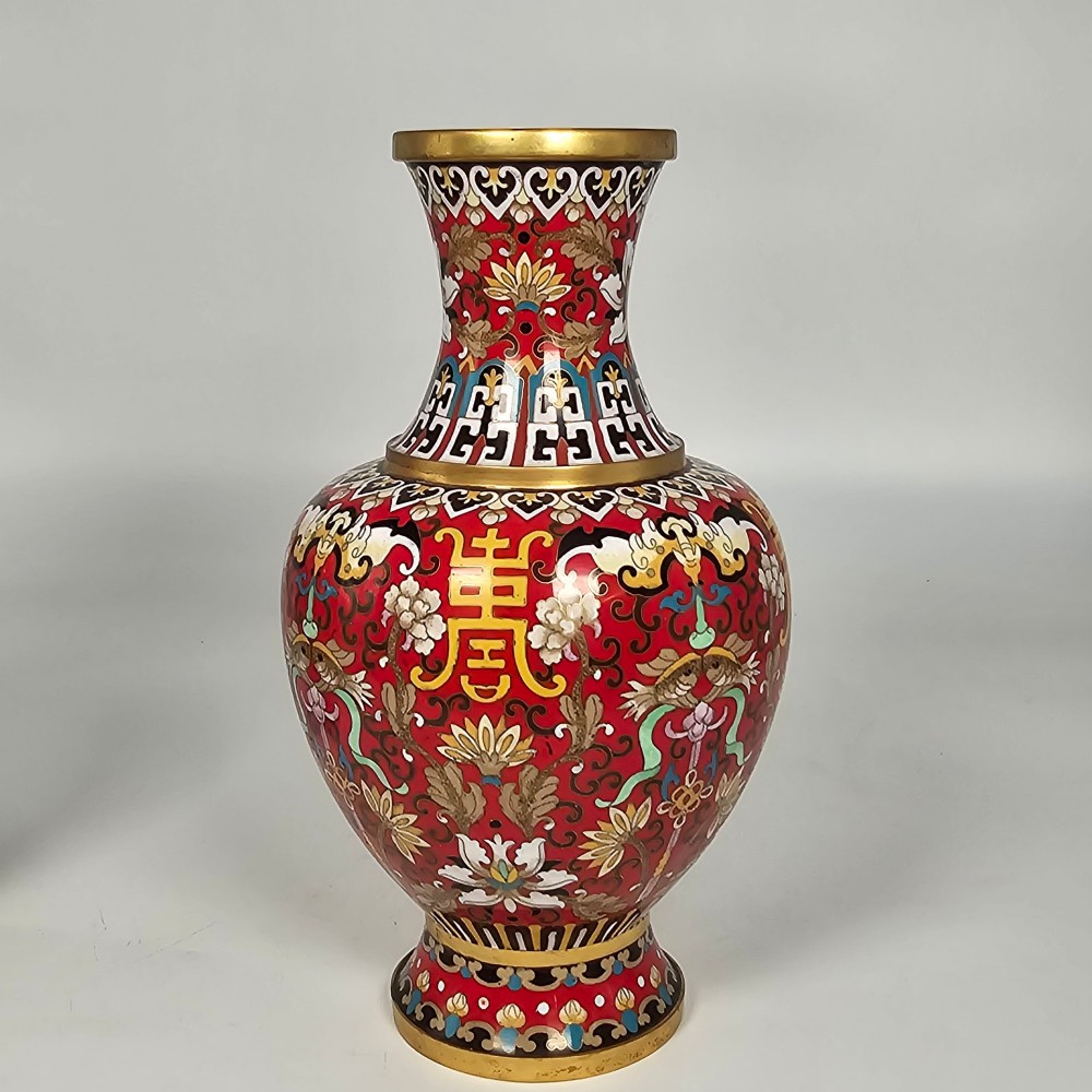 A matching pair of baluster-form Chinese cloisonne enamel vases with red backgrounds, lotus motifs, auspicious symbols, and gilt rims. View VII