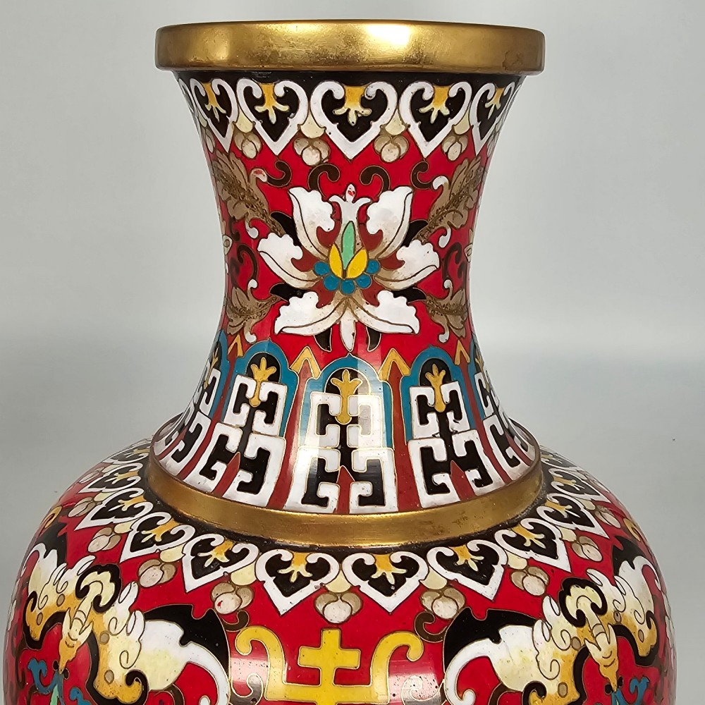 A matching pair of baluster-form Chinese cloisonne enamel vases with red backgrounds, lotus motifs, auspicious symbols, and gilt rims. View IX