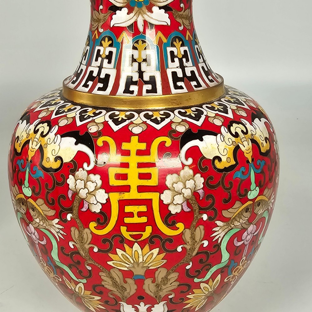 A matching pair of baluster-form Chinese cloisonne enamel vases with red backgrounds, lotus motifs, auspicious symbols, and gilt rims. View X