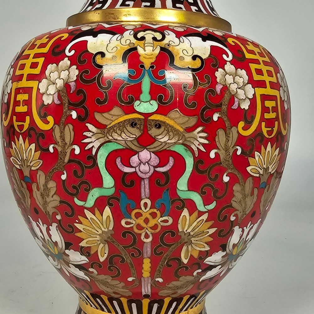 A matching pair of baluster-form Chinese cloisonne enamel vases with red backgrounds, lotus motifs, auspicious symbols, and gilt rims. View XI