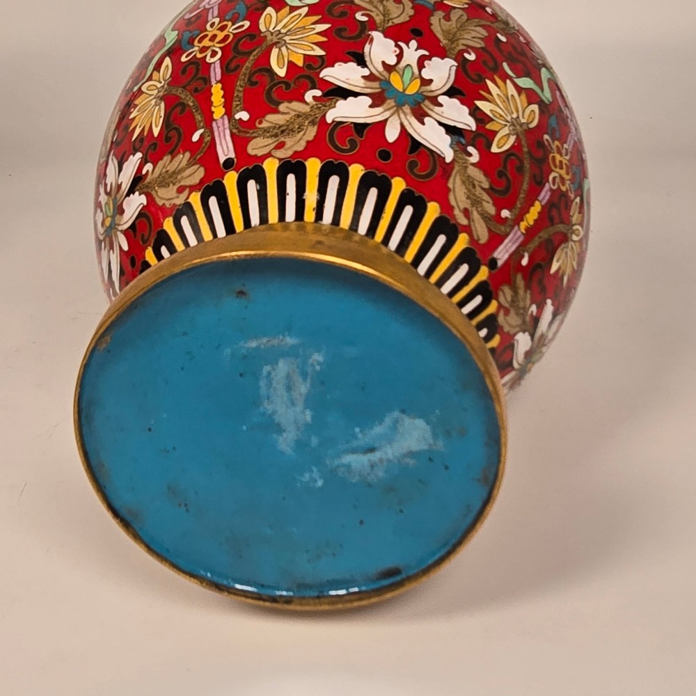 A matching pair of baluster-form Chinese cloisonne enamel vases with red backgrounds, lotus motifs, auspicious symbols, and gilt rims. View XIV
