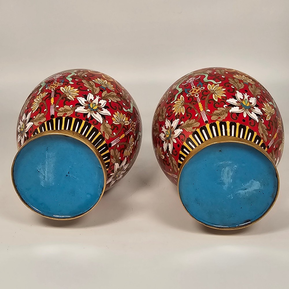 A matching pair of baluster-form Chinese cloisonne enamel vases with red backgrounds, lotus motifs, auspicious symbols, and gilt rims. View XV