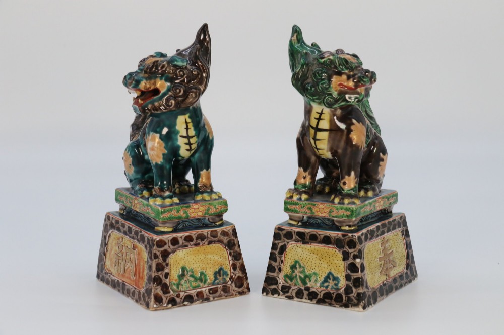 A pair of glazed Chinese ceramic Buddhist lion figures decorated in green, brown, and yellow glazes resting on patterned pedestal bases. View III