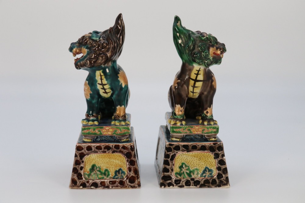 A pair of glazed Chinese ceramic Buddhist lion figures decorated in green, brown, and yellow glazes resting on patterned pedestal bases. View IV