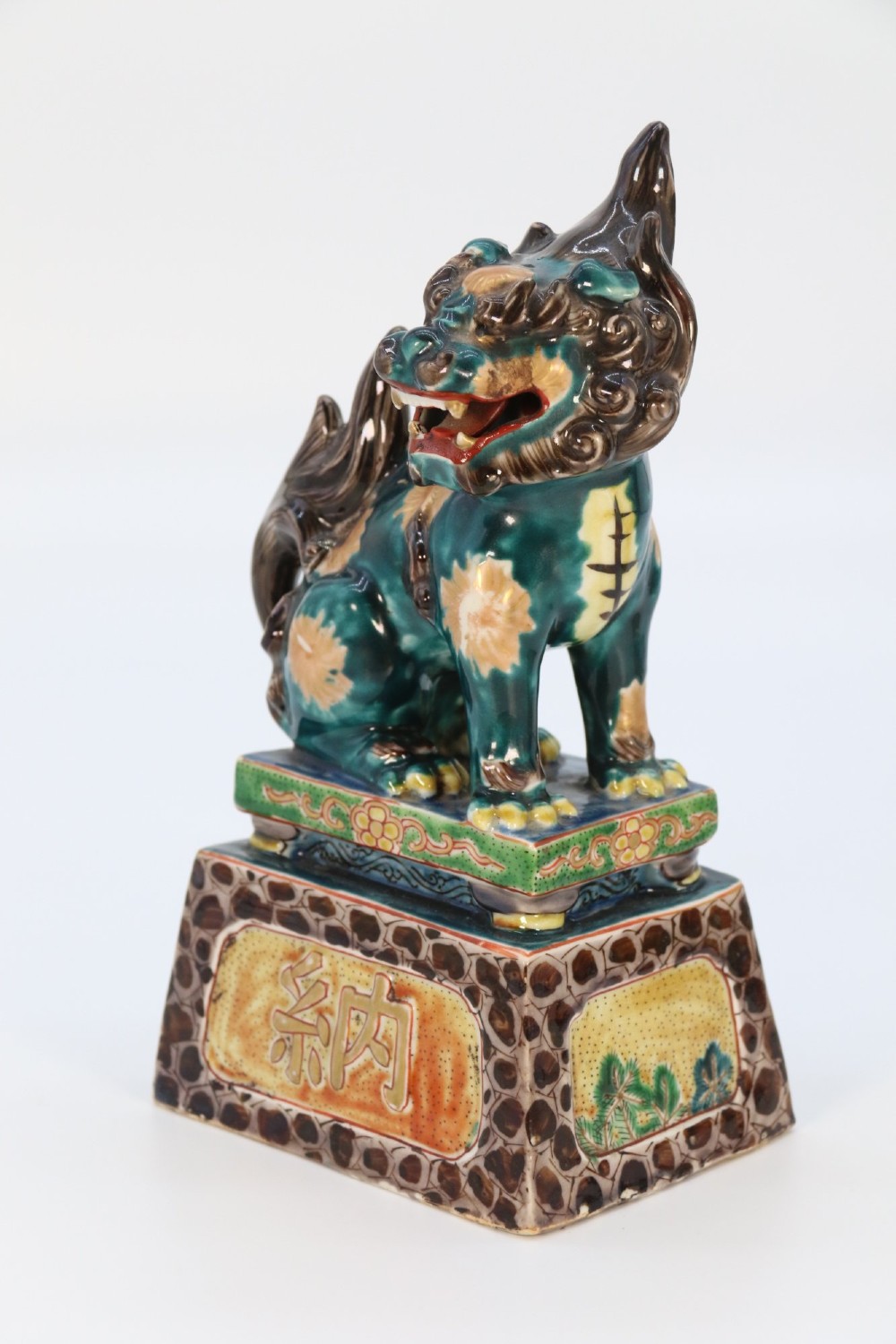 A pair of glazed Chinese ceramic Buddhist lion figures decorated in green, brown, and yellow glazes resting on patterned pedestal bases. View XI
