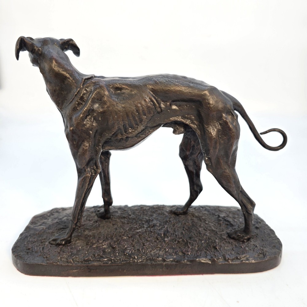 A 19th-century dark patinated bronze sculpture of a standing greyhound dog on a textured oval base. View IV