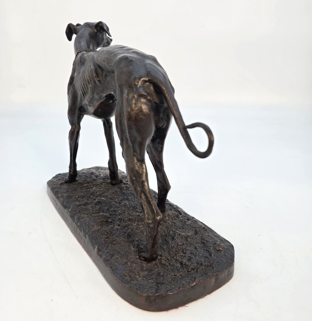 A 19th-century dark patinated bronze sculpture of a standing greyhound dog on a textured oval base. View V