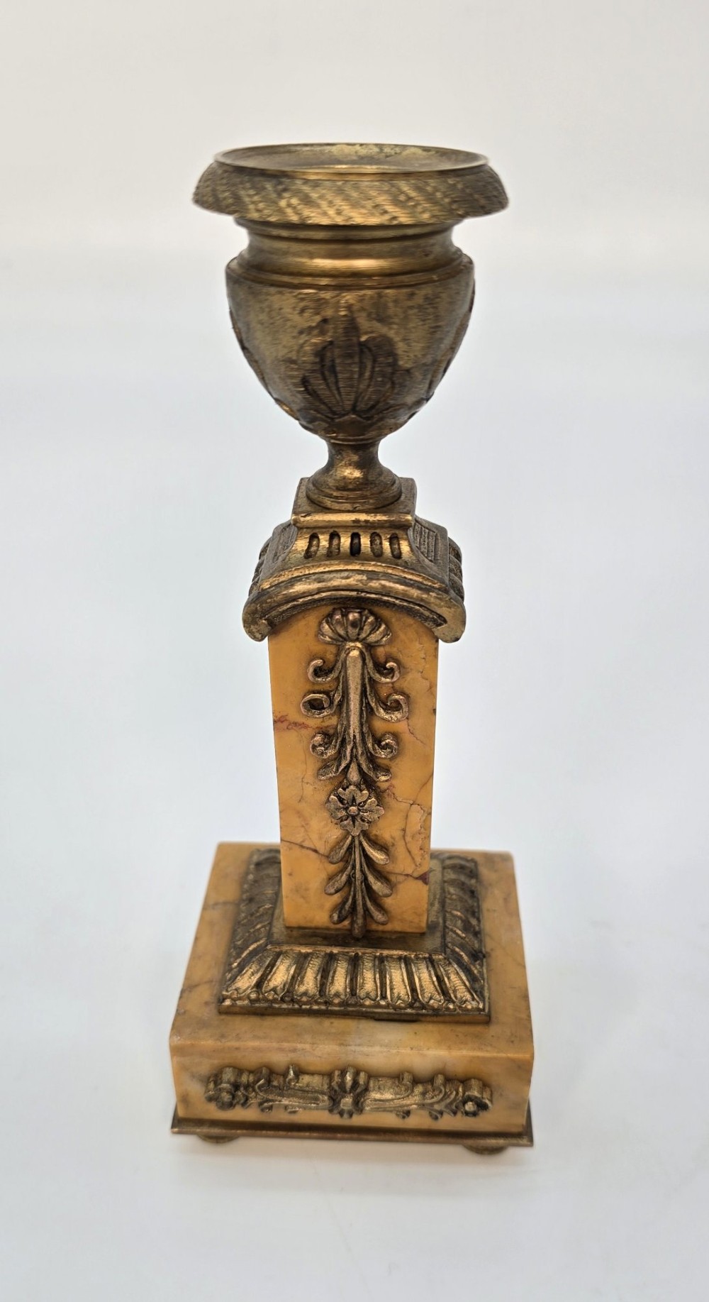A pair of nineteenth-century French Empire gilt-bronze candlesticks featuring urn-shaped nozzles and applied bronze foliage on rectangular yellow marble bases. View II