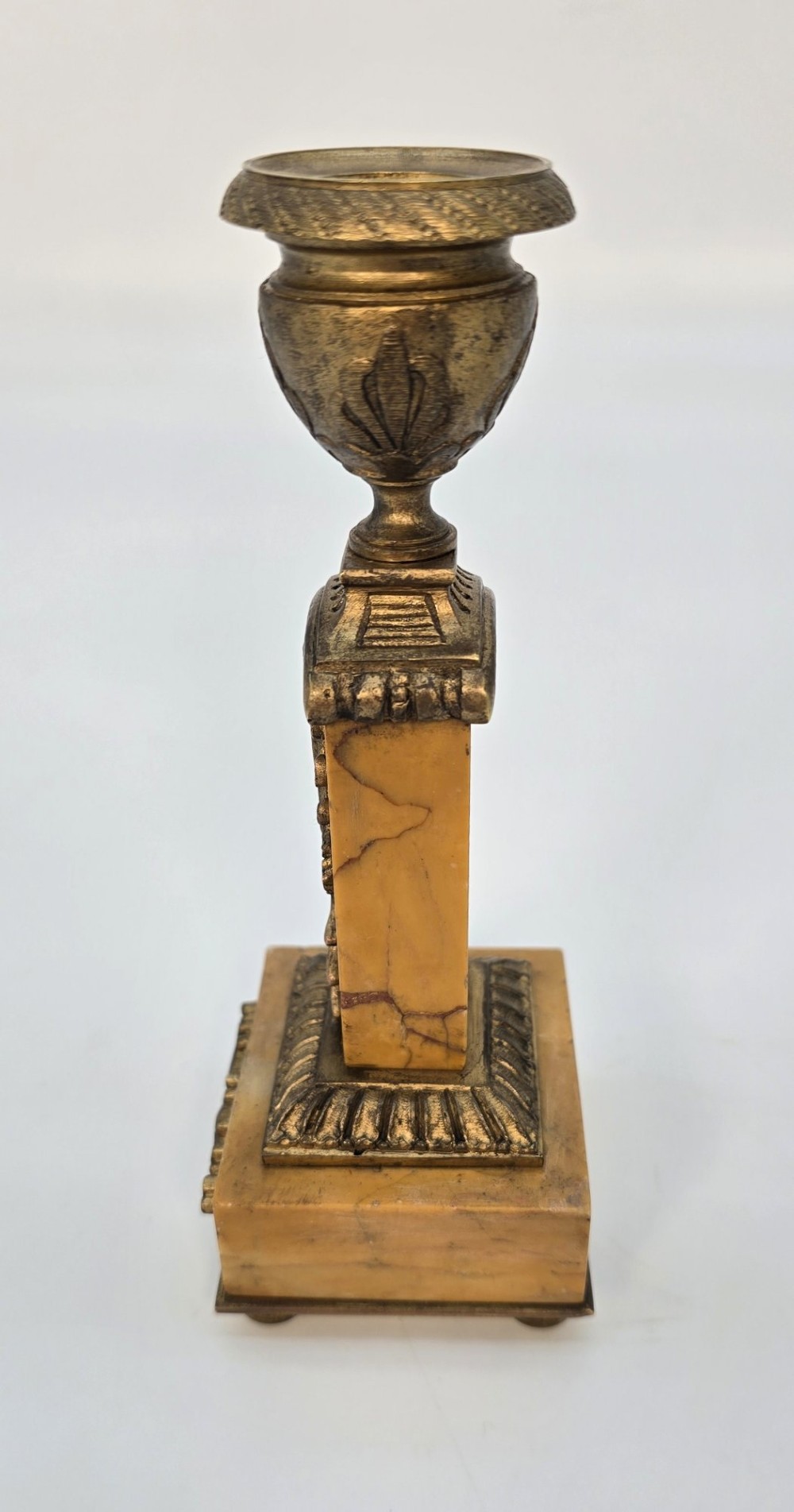 A pair of nineteenth-century French Empire gilt-bronze candlesticks featuring urn-shaped nozzles and applied bronze foliage on rectangular yellow marble bases. View IV