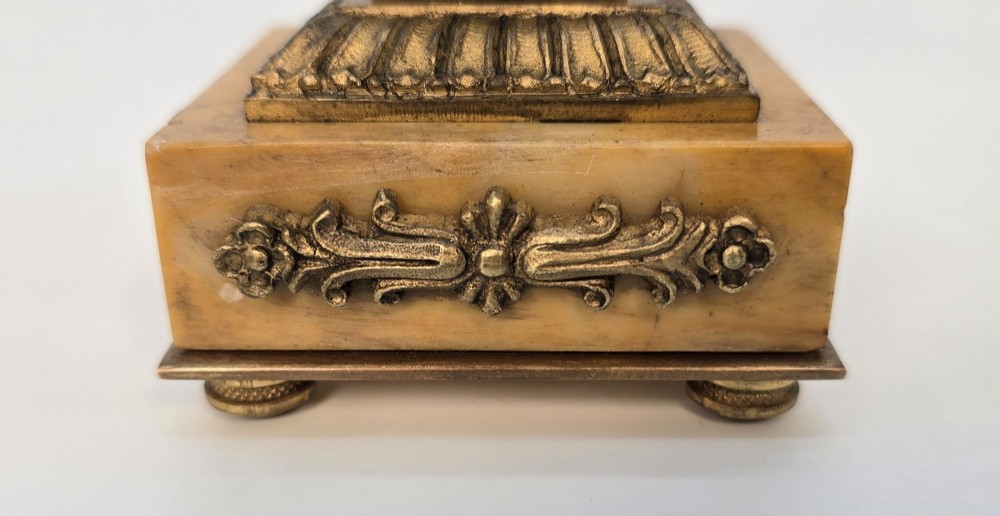 A pair of nineteenth-century French Empire gilt-bronze candlesticks featuring urn-shaped nozzles and applied bronze foliage on rectangular yellow marble bases. View IX