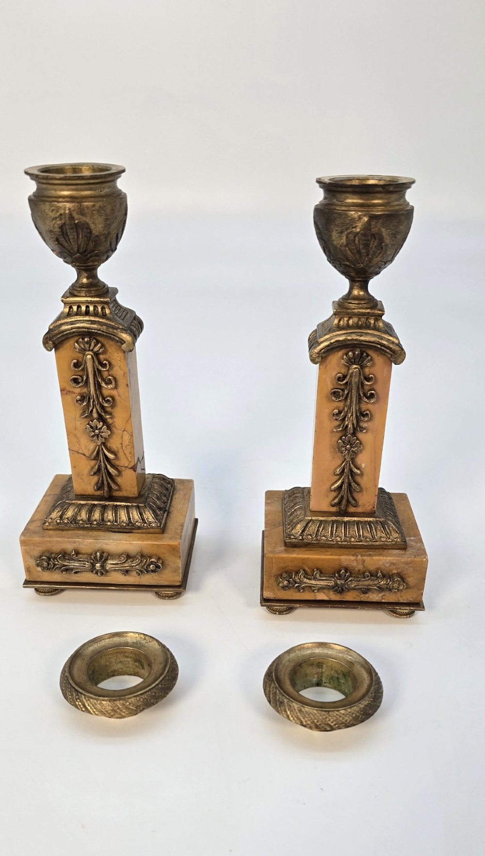 A pair of nineteenth-century French Empire gilt-bronze candlesticks featuring urn-shaped nozzles and applied bronze foliage on rectangular yellow marble bases. View X