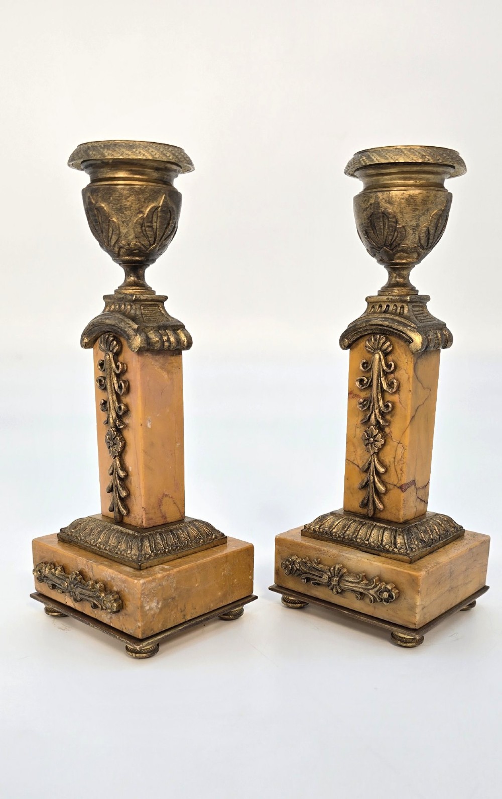 A pair of nineteenth-century French Empire gilt-bronze candlesticks featuring urn-shaped nozzles and applied bronze foliage on rectangular yellow marble bases. View XI