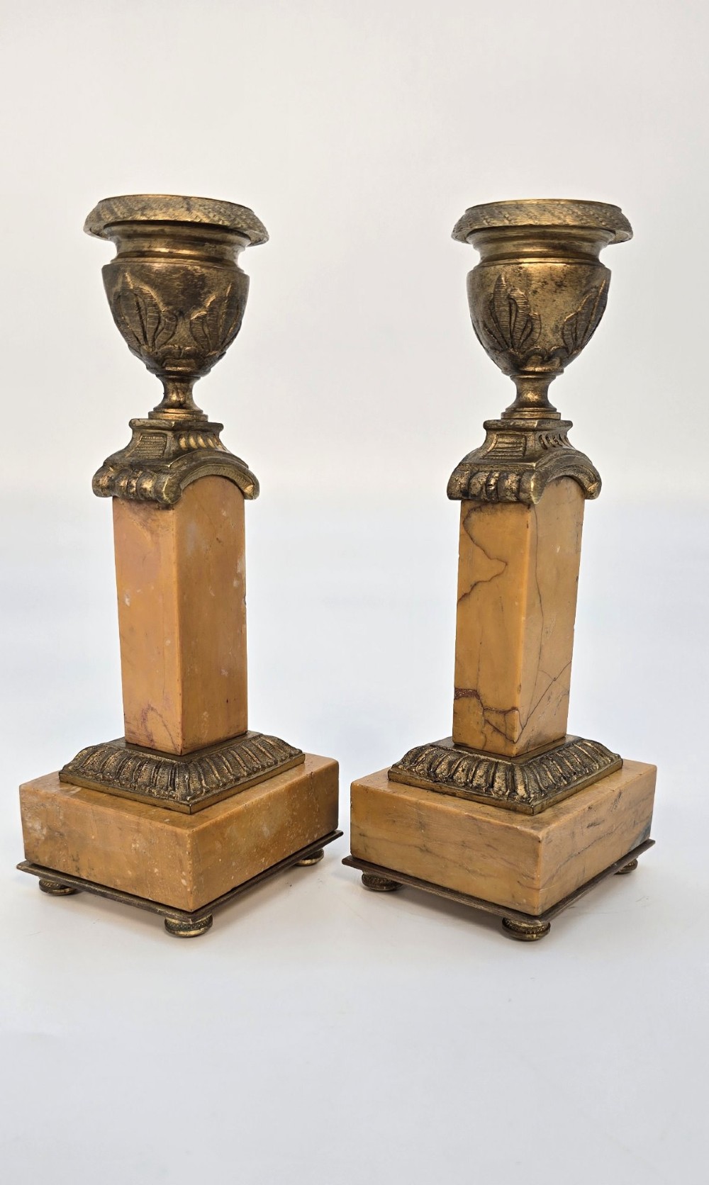 A pair of nineteenth-century French Empire gilt-bronze candlesticks featuring urn-shaped nozzles and applied bronze foliage on rectangular yellow marble bases. View XIII