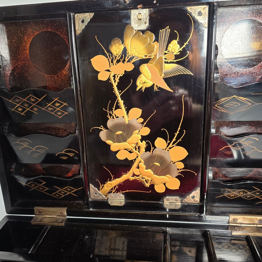 An open black lacquer writing box decorated with gold floral and bird motifs, revealing internal stationery compartments. View XI